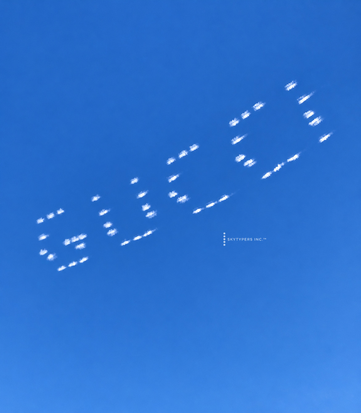A short dotted sky message photographed diagonally against blue sky.
