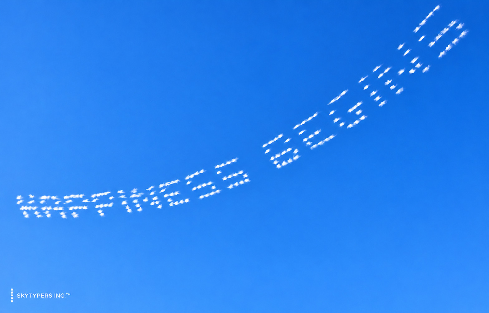 HAPPINESS BEGINS written across a clear blue sky.