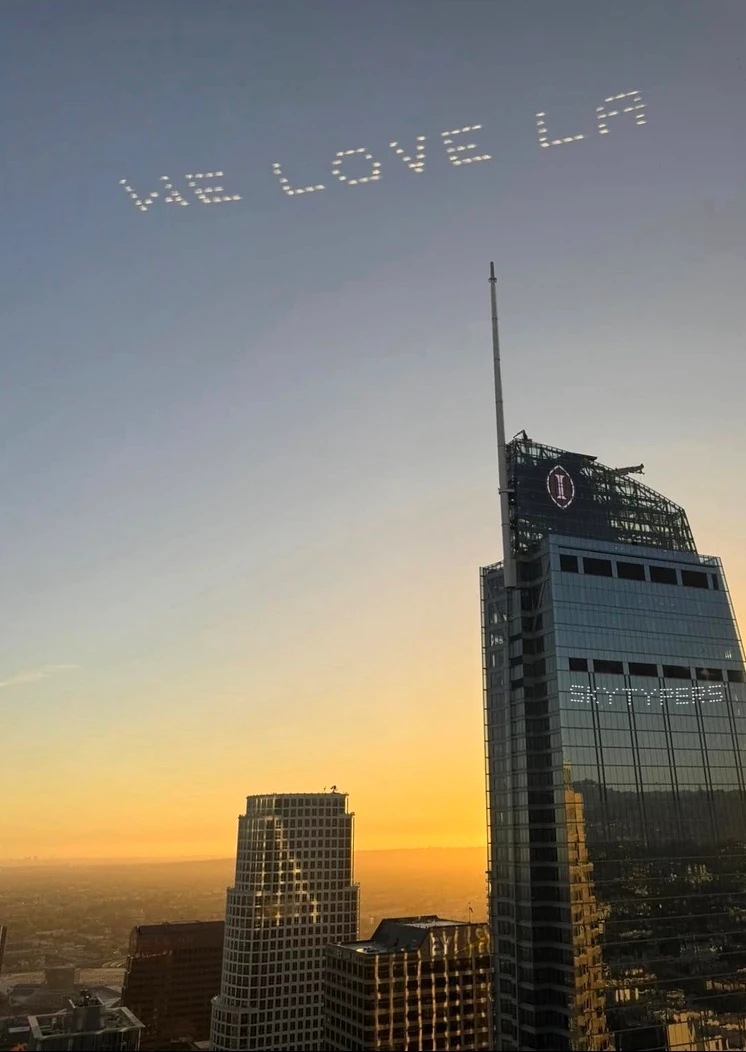 WE LOVE LA skytyping above the Los Angeles skyline in warm evening light.