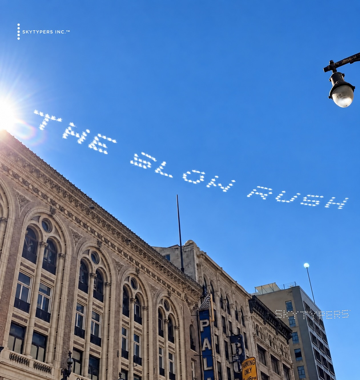 The Slow Rush spelled in white skytyping above a historic Los Angeles building under a blue sky.