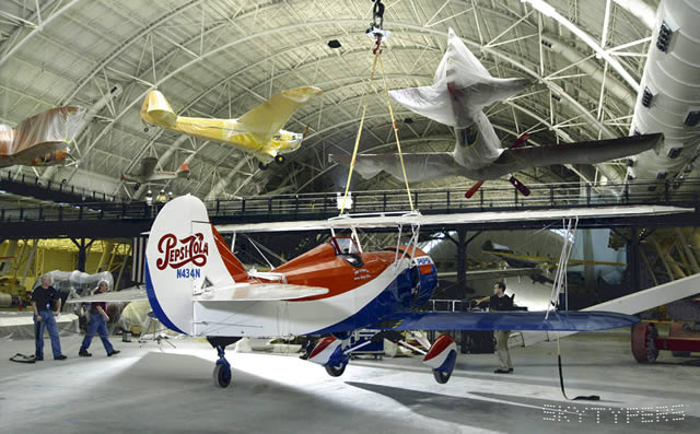 Pepsi-Cola biplane on an indoor display floor.