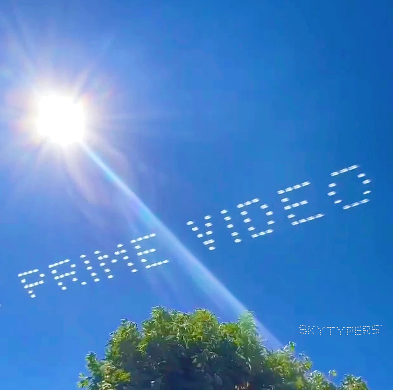 PRIME VIDEO written in white skytyping dots across a blue sky, with sunlight and a tree in the frame.