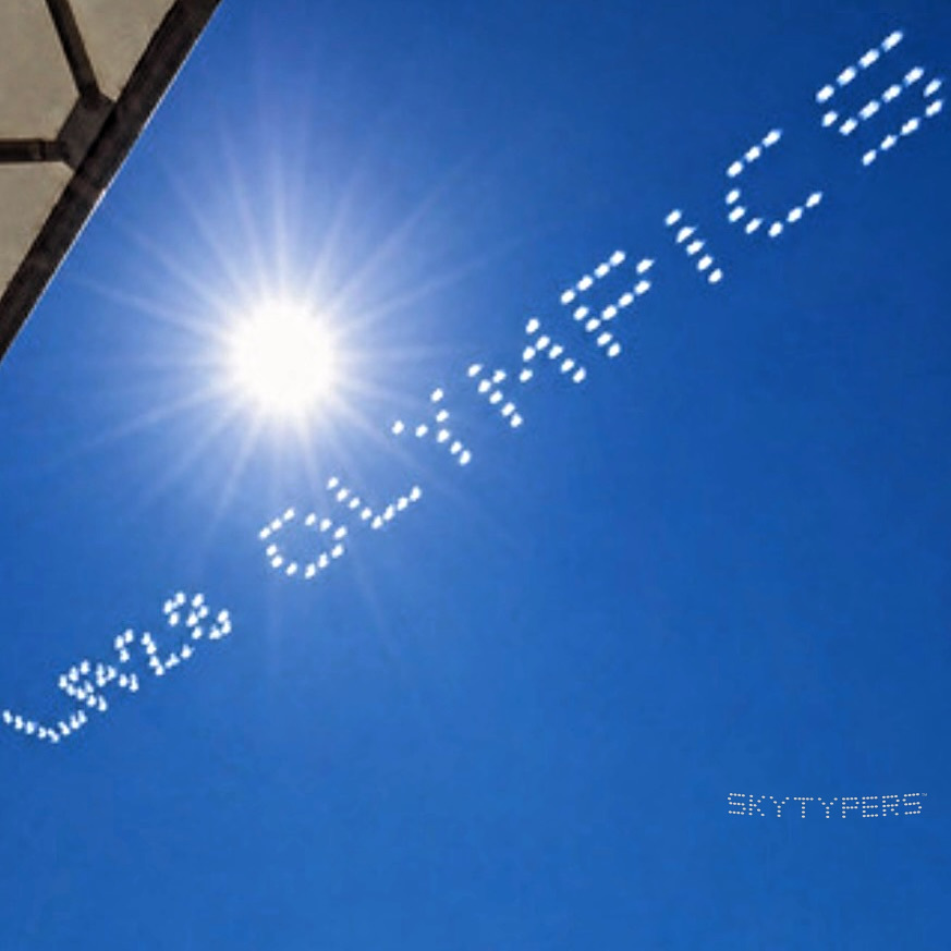 White dot-matrix LA28 Olympics lettering crosses a deep blue sky beside a bright sunburst.