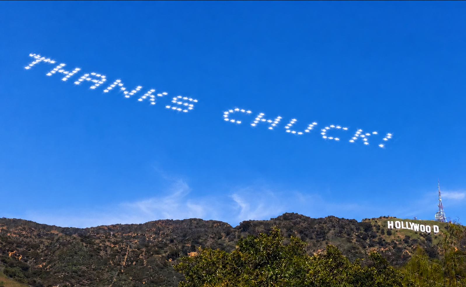 THANKS CHUCK! in bright white dotted smoke above the Hollywood sign and hills.
