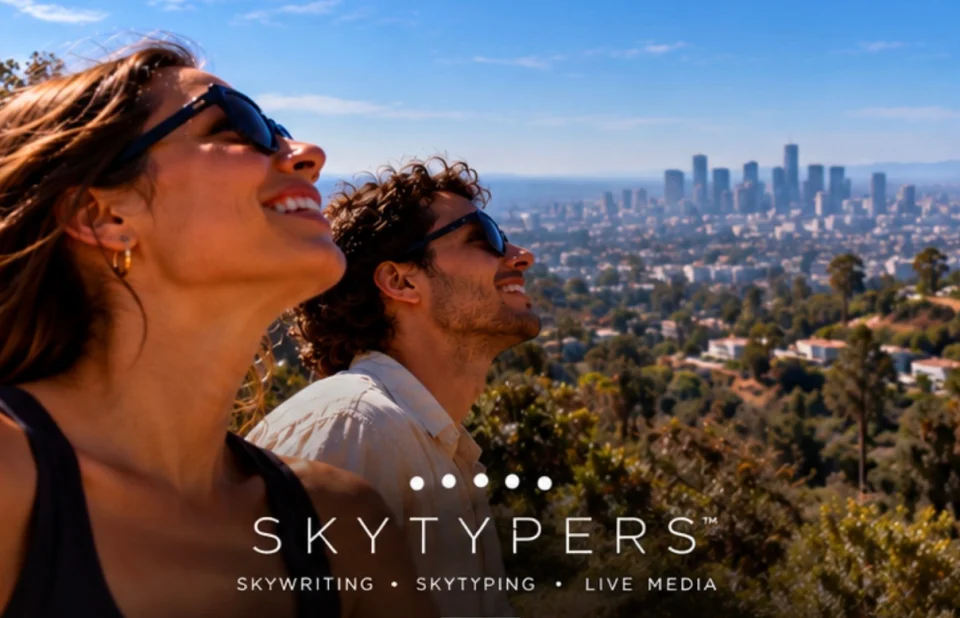 Two people smiling and looking up above Los Angeles, with Skytypers branding